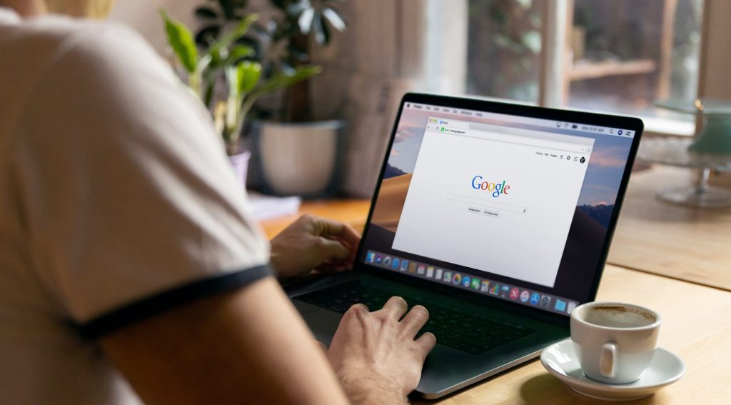 Man uses Apple MacBook in a cafe or restaurant. He is searching Google website. Free editable PSD here: https://firmbee.com/unsplashscreen3