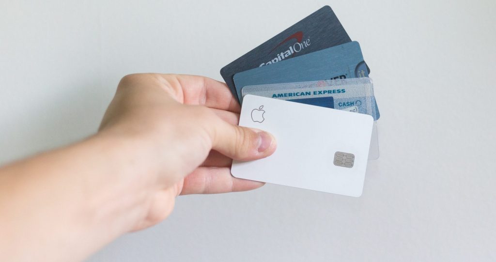 A person holding credit cards against a white background wall.