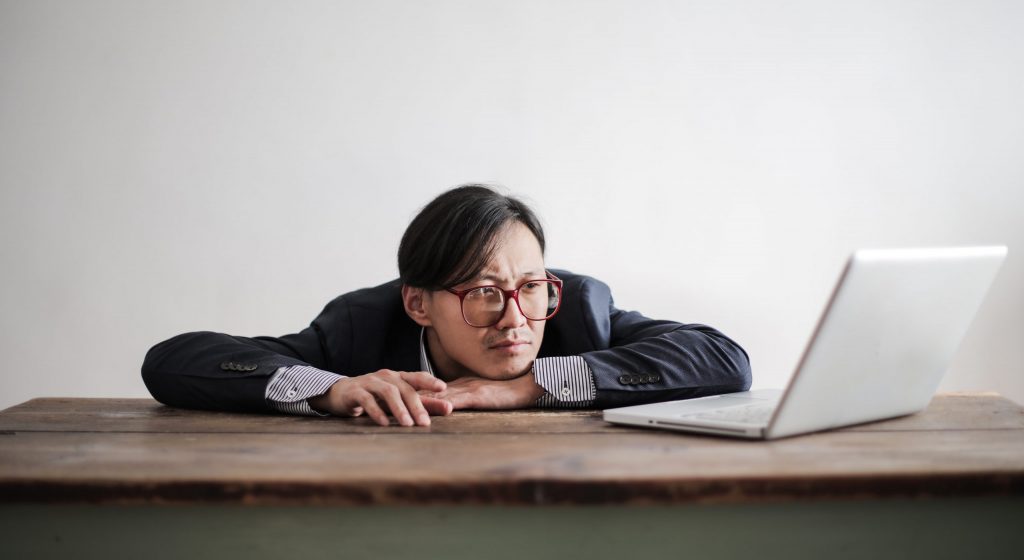 Bored formal man watching laptop at desk