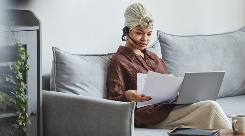 Focused black woman with laptop examining documents