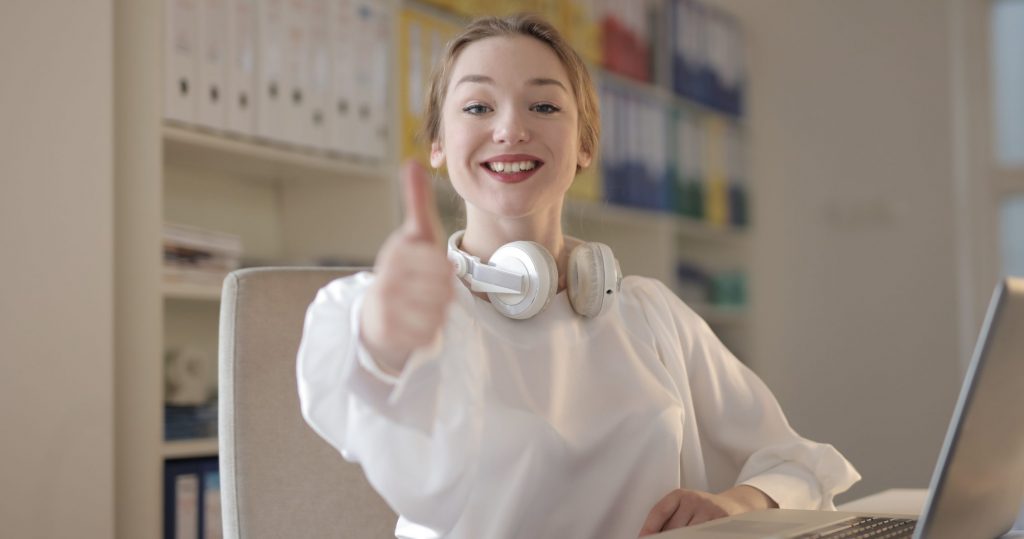 Woman wearing white top while doing thumbs up