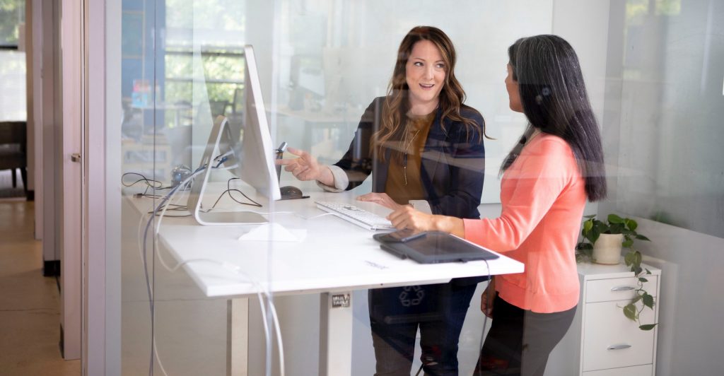 Two women at standing desk working