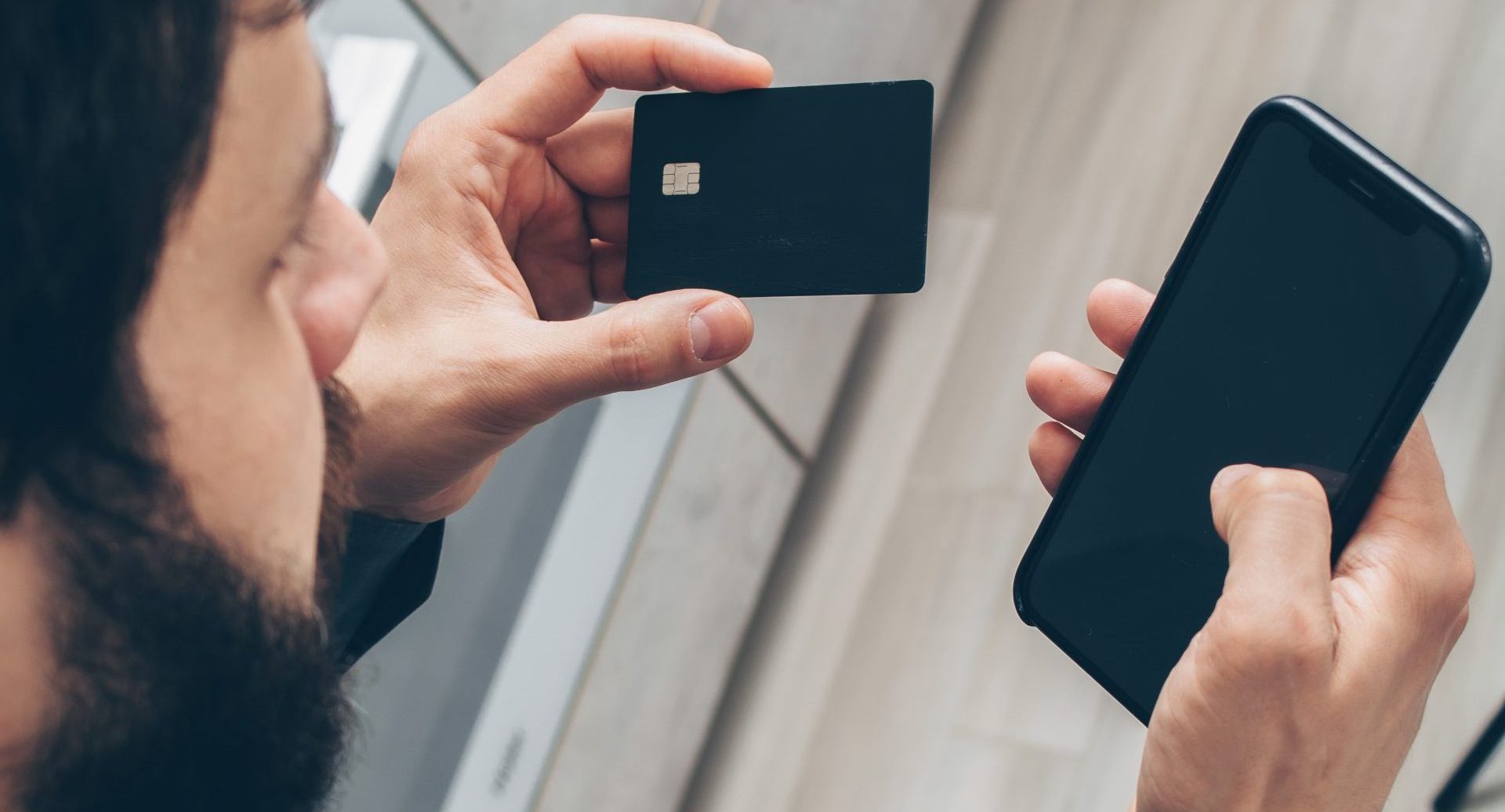 Man in gray sweater holding black smartphone