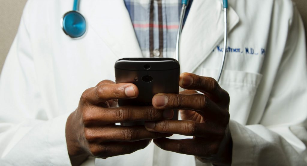 Doctor Holding Cell Phone. Cell phones and other kinds of mobile devices and communications technologies are of increasing importance in the delivery of health care. Photographer Daniel Sone