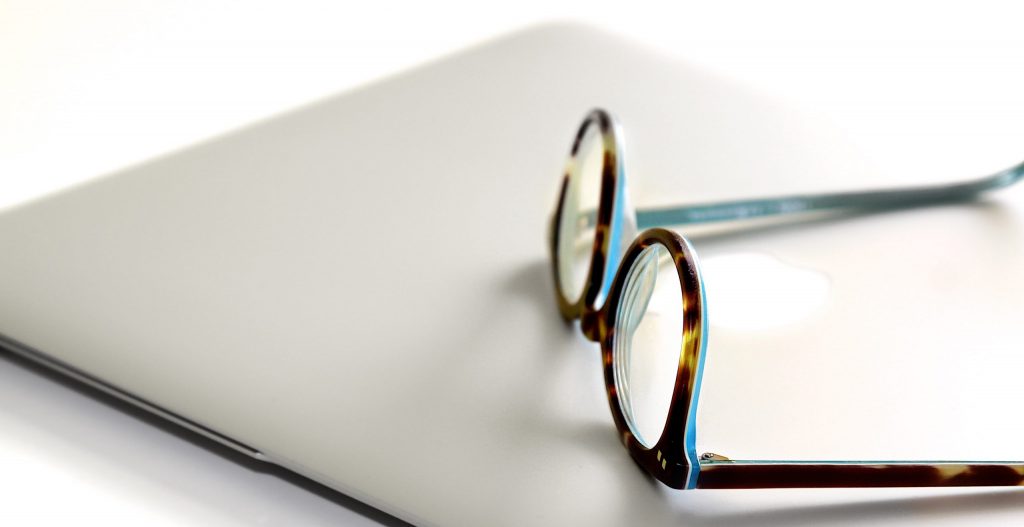 Black and blue framed eyeglasses on silver laptop