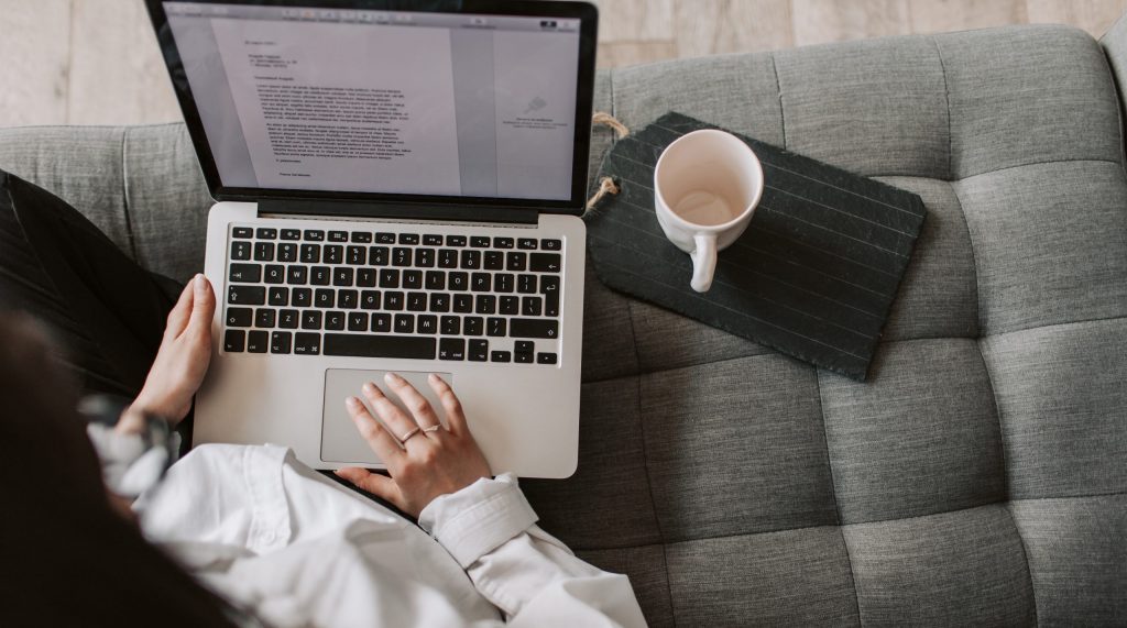 Crop woman using laptop on sofa at home