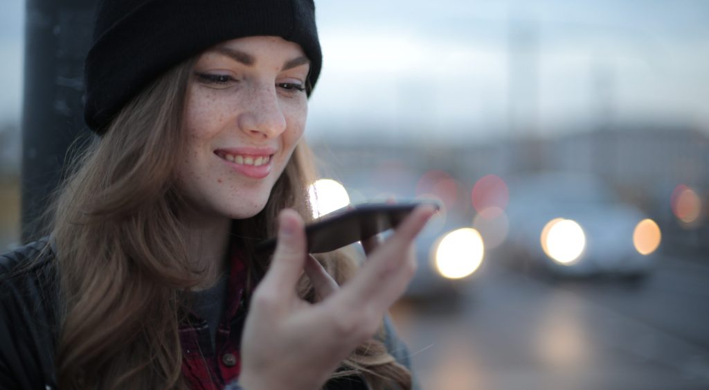 Joyful young woman phoning on street in evening