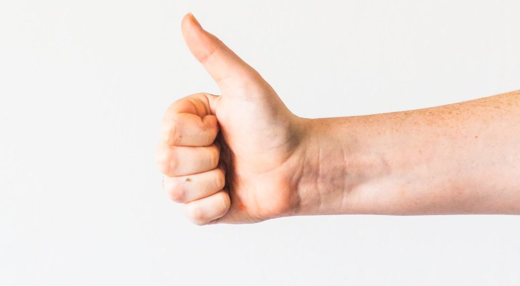 persons right hand doing thumbs up